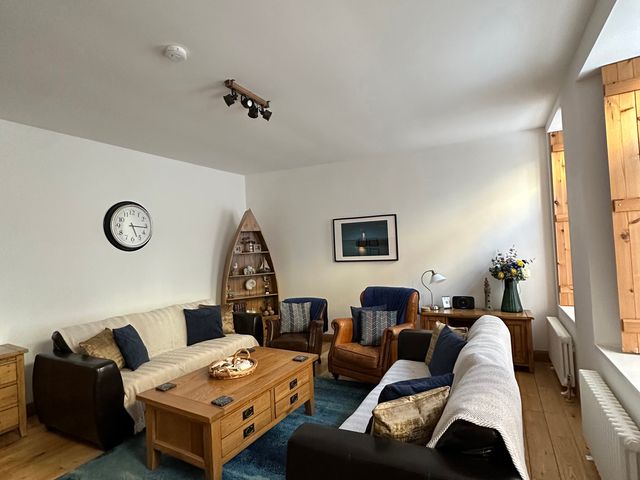 A living room with a coffee table, sofa, and armchairs at Coastal Cottage in Anstruther