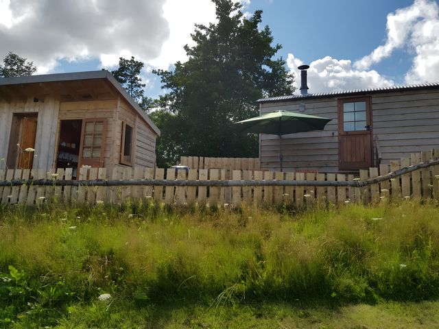A cabin with a fence and umbrella at Bryn Mawr Cabin in Craven Arms
