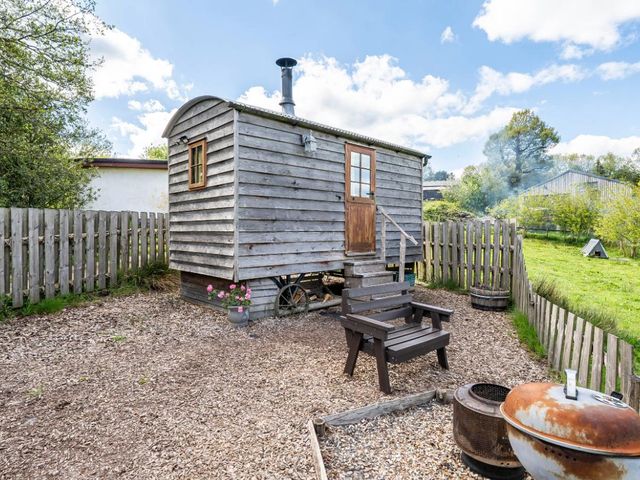 An outdoor area with a wooden cabin and seating at Bryn Mawr Cabin in Clun