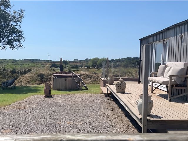 An outdoor area with decking chairs and a hot tub at The lodge at Plumstone View Haverfordwest