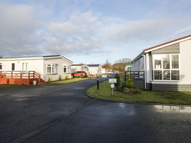 A view of mobile homes with a pathway and vehicles at Beechtree Timber Lodge 69B in Denny