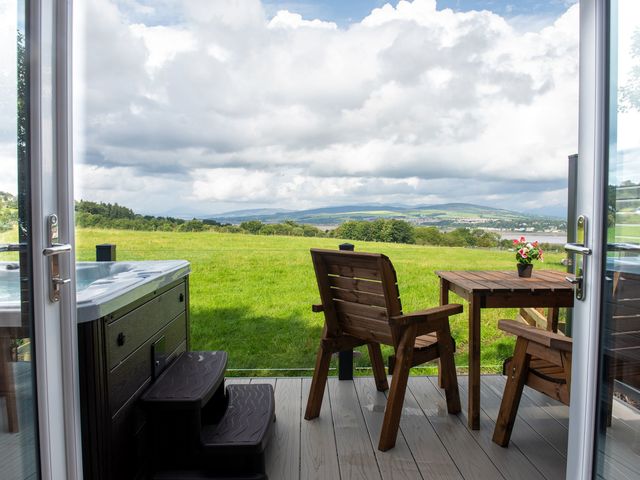 An outdoor seating area with a hot tub and table at Nethermill Lodges in Port Glasgow