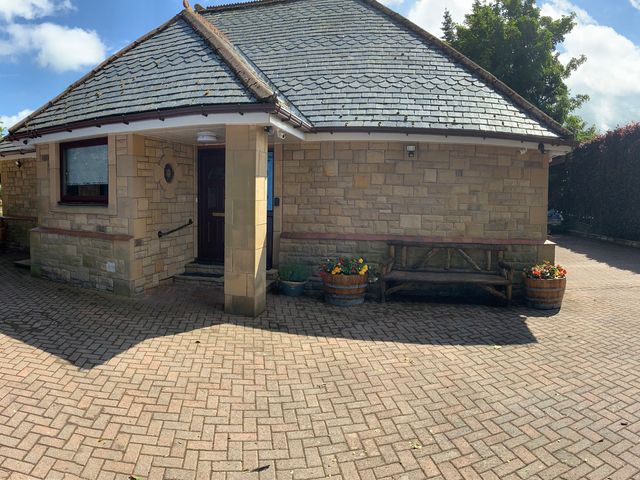 A house with a brick pathway and flower pots at Fenton Drive Wooler