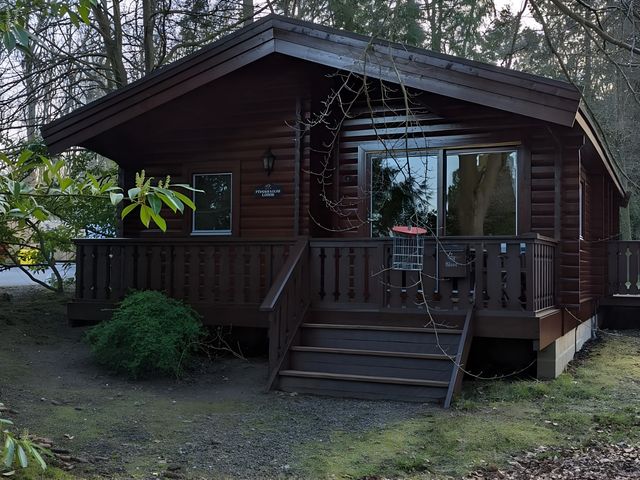 A log cabin with a deck and stairs at Pineshadow Lodge in Louth