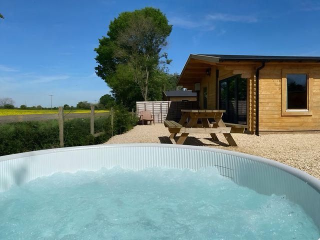 A hot tub and picnic table near a wooden cabin at Cotswold Nights in Evesham