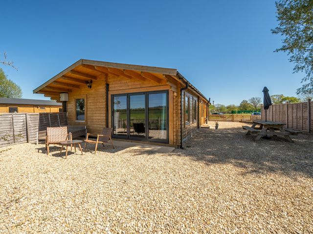 A wooden cabin with outdoor seating area at Cotswold Nights Ashton Under Hill