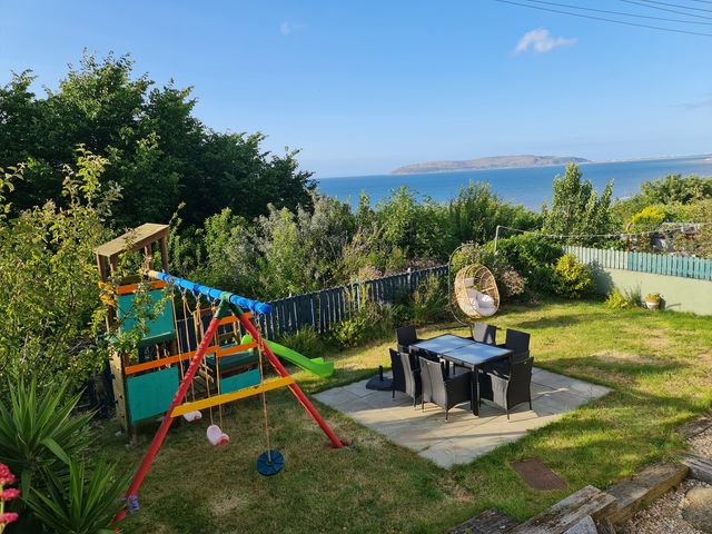 A garden with a swing set and dining area at Sea view cottage Penmaenmawr