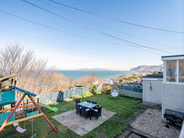 A garden with a swing set and dining area at Sea view cottage Penmaenmawr