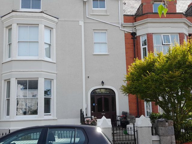 A house exterior with entrance and vehicle in front at 2nd Floor Apartment in Llandudno