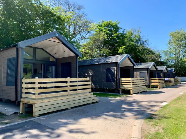 A row of wooden cabins with fences in an outdoor area at Inverness Lodge in Inverness