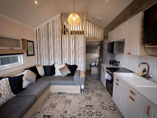 A living room with a sofa and kitchen area at Inverness Lodge in Inverness