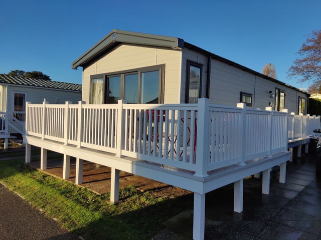 A mobile home with a deck and railing at Harbour View in Poole