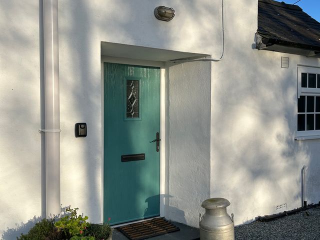 A blue door with a letterbox and light fixture at Bodior Garden Cottage Bach Rhoscolyn