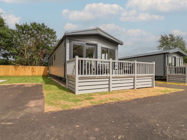 A mobile home with a deck in front at The Oaks 2 Bedrooms Delamere