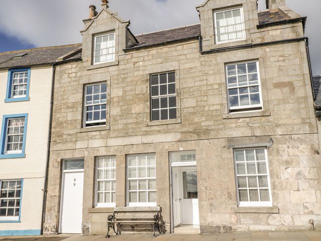 A building facade with windows and a bench at Maimie’s Harbourview in Anstruther