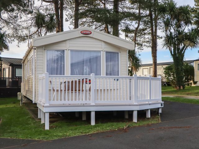 A caravan with a deck and table at Caravan A24 at Landscove Holiday Park Brixham