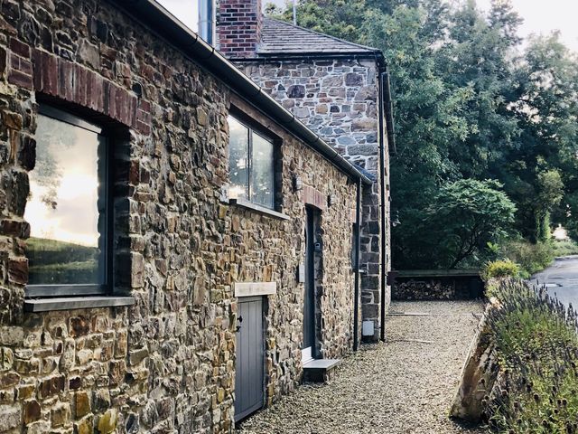 An outdoor view of a stone building with windows and a door at Meadow View in Widemouth Bay