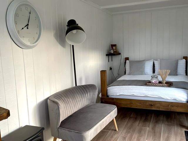 A bedroom with a bed and a seating area at Trethowels Hidden Huts in St. Austell