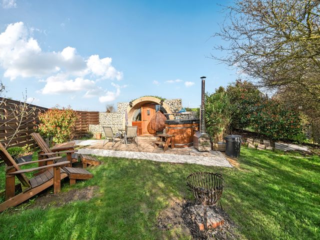 An outdoor garden with a hot tub, wooden chairs and fire pit at Cosy Escape in Minster On Sea