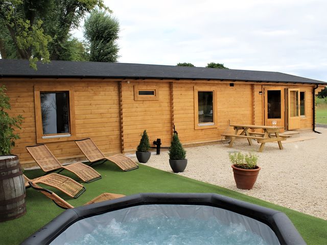 An outdoor area with a cabin, hot tub, and wooden furniture at Cotswold Nights Away in Evesham