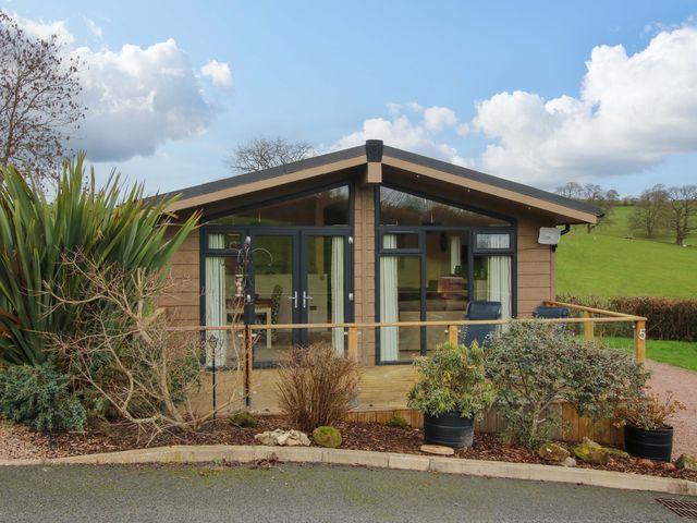 A lodge with a wooden deck and plants at 5 Hillview Lodges in Cleobury Mortimer