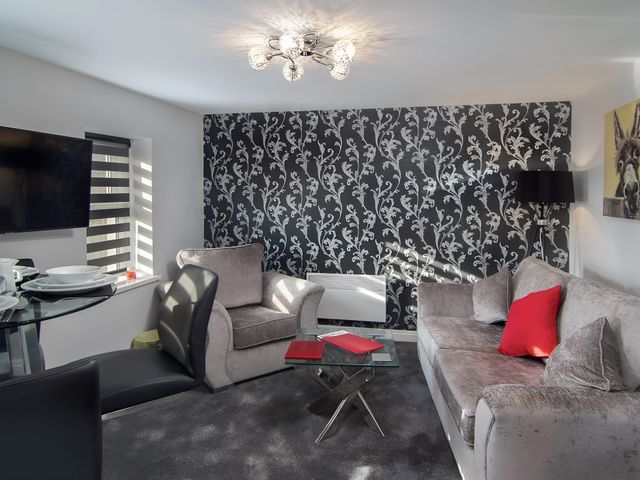 A living room with a sofa, armchair, and dining area at Apartment 3 in Blackpool