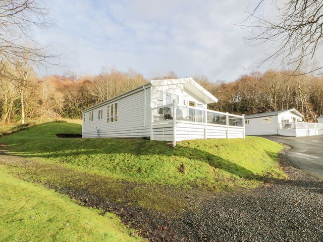 A house with a deck and driveway at Serenity Lodge in Wemyss Bay