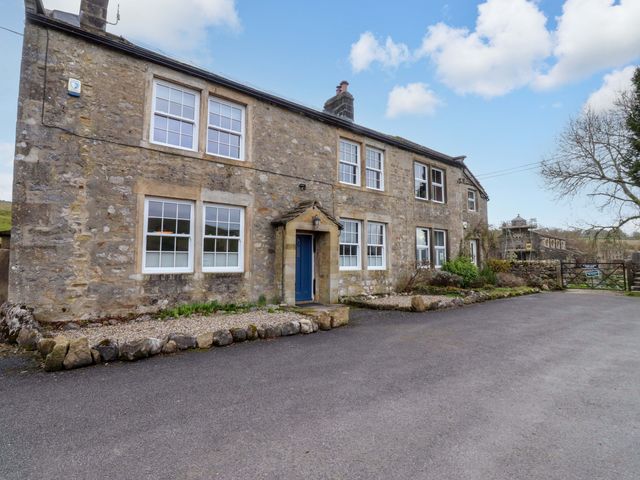A stone building with windows and a blue door at Kirk Yett in Skipton