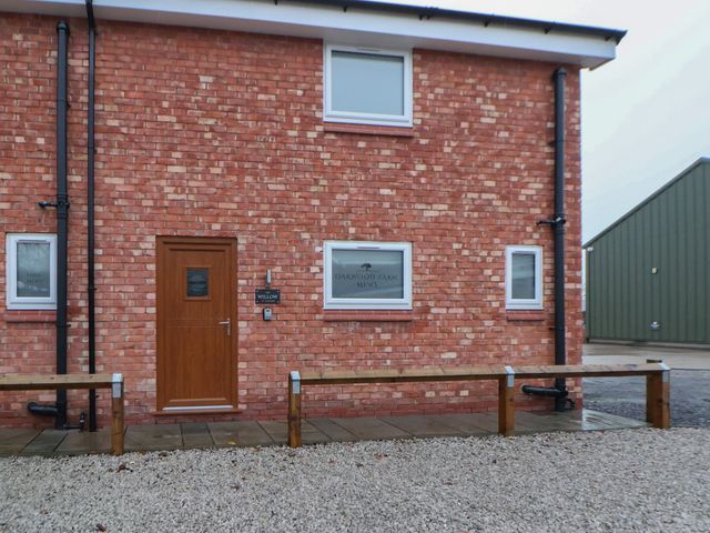 An exterior view of a brick building with a wooden door and windows at Willow Barn in Chester