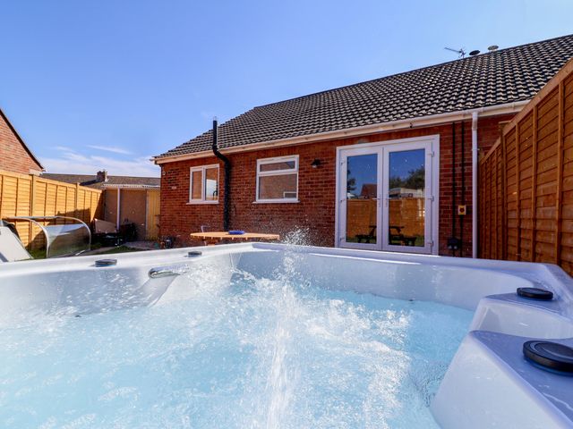 A hot tub in a garden beside a brick wall at 1 Ashcott Place Burnham-On-Sea