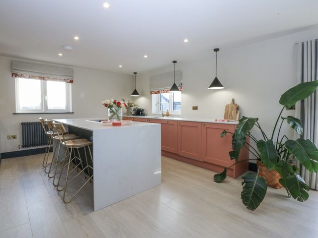 A kitchen with a kitchen island and bar stools at Bell House in Llanfechell