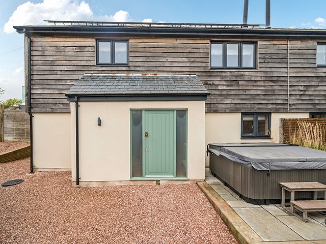 An outdoor area with a hot tub and a green door at Bell House in Llanfechell