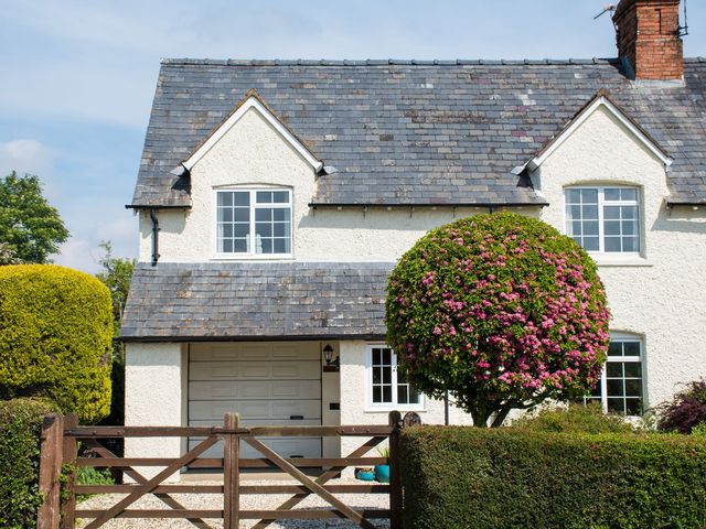 A house with a garage door and a landscaped garden at Glencoe Cottage in Broadway