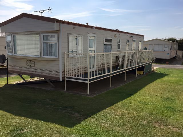 A caravan with a railing on a grassy area at Gannet 18 (G18) Bridlington