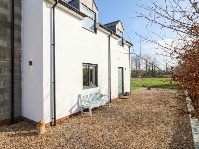 An exterior view of a house with a bench and gravel area at The Kiln in Colmworth