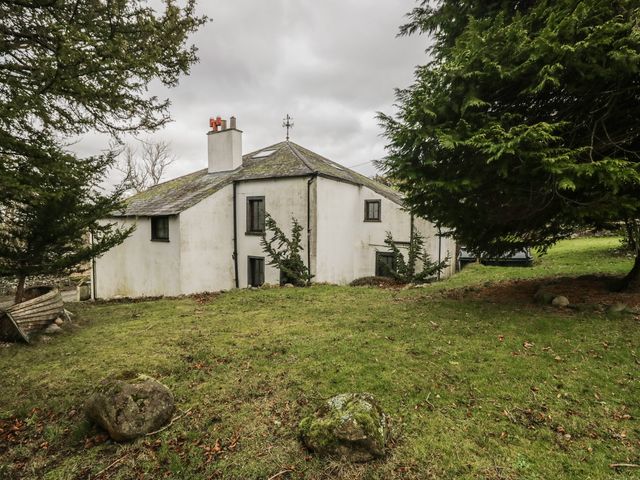 A house surrounded by grass and trees at Birkbank Farm in Cockermouth