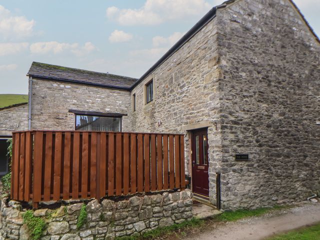 An outdoor view of a stone building with a wooden railing and door at The Forge in Castleton, Peak District