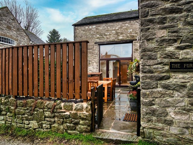 An outdoor dining area with a wooden table and chairs at The Forge in Castleton, Peak District
