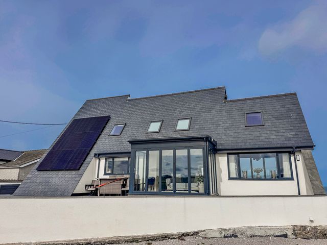 A house with solar panels and large windows at Pengarnedd Amlwch