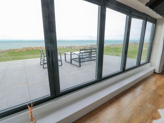 A living room with a view of the patio and sea at Pengarnedd Amlwch