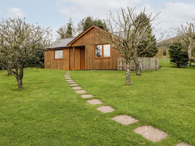 A cottage with a path and trees at Orchard Cottage in Ledbury