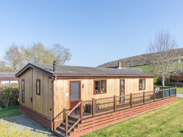 A wooden lodge with a deck and steps at Hazel Lodge in Craven Arms