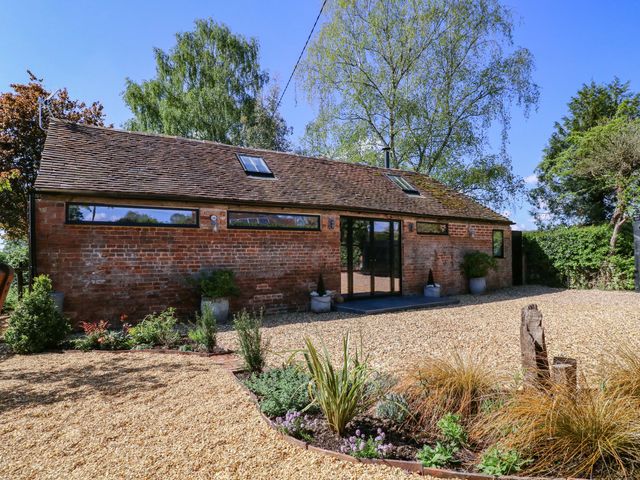 An exterior view of a brick building with surrounding plants and gravel at The Barn