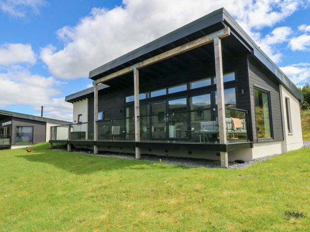 A house with a deck and glass railing in a green area at Strathview