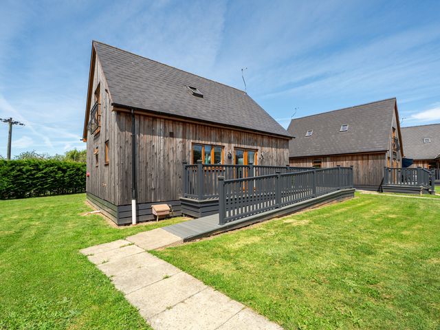 A wooden house with a deck and grass area at James Ville Marina Lodge 7 Brigg