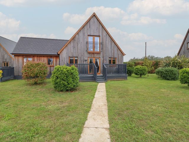 An outdoor view of a wooden house with a deck and bushes at James Ville Marina Lodge 9 in Brigg