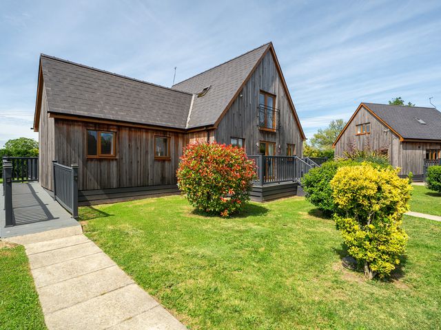A wooden house with a balcony and garden at James Ville Marina Lodge 9 Brigg