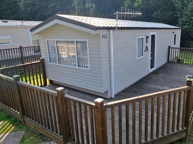 A mobile home with a wooden deck at N5 Ilfracombe