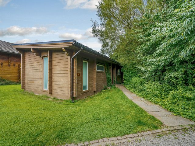 A wooden building with windows and a pathway at Poplar Lodge (Pet) Thirsk