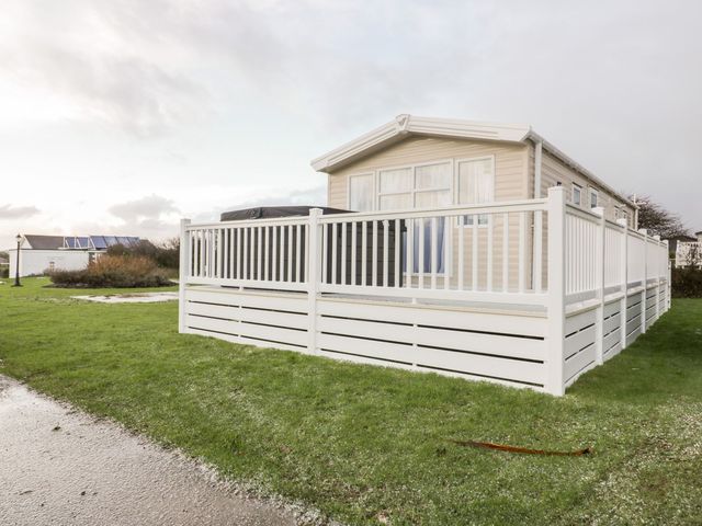 A mobile home with a deck and fence at Barney's Retreat in Newquay